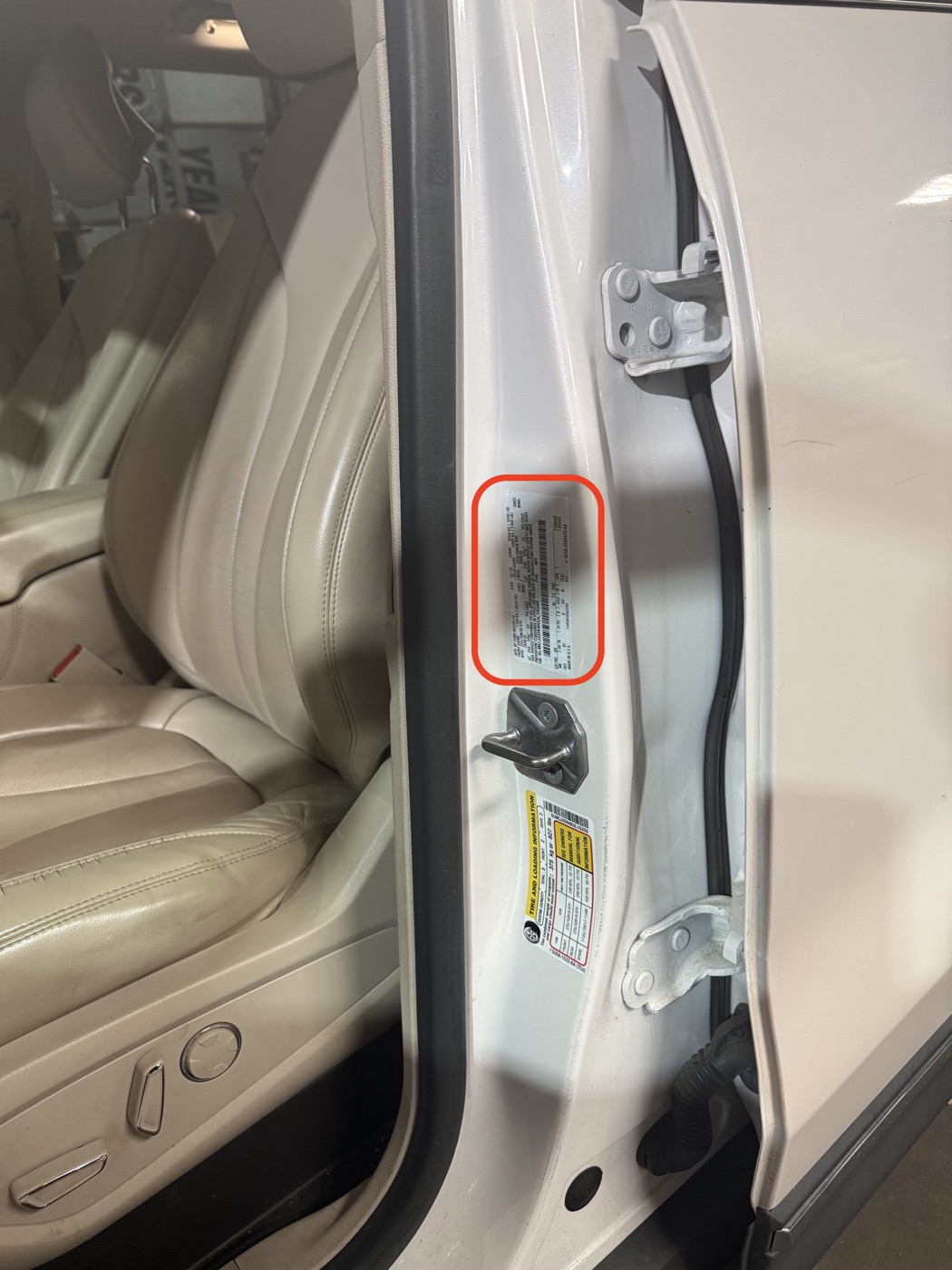 The sticker is on the driver's door jamb — open the door and look where the red circle shows.